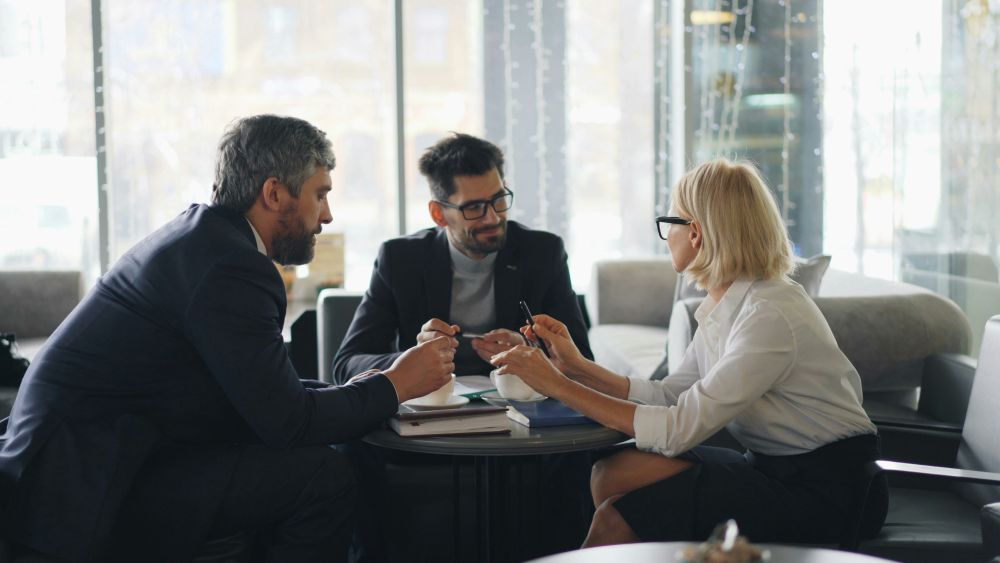 Trois professionnels échangent autour d'une table basse